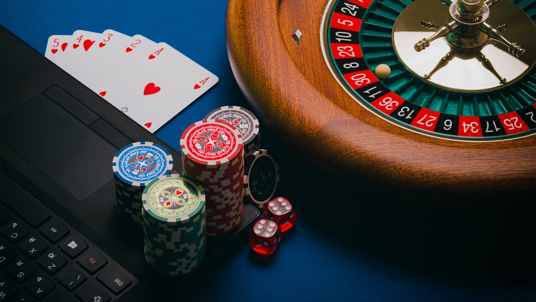 An assortment of poker chips, a roulette wheel, playing cards, and a laptop on a blue background.